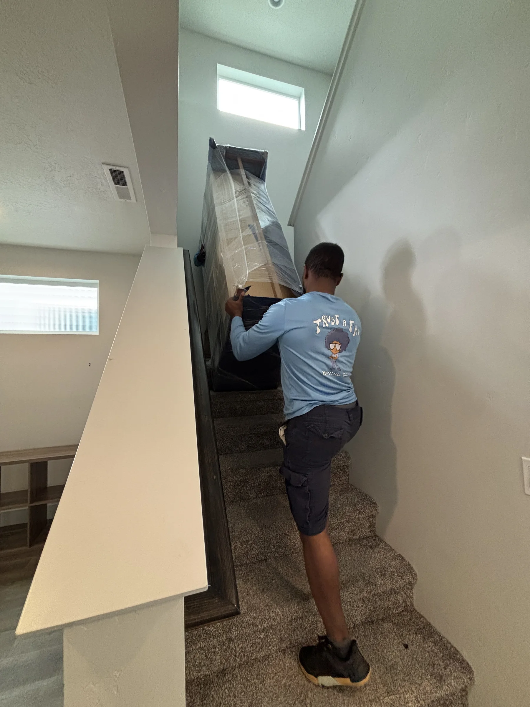 A mover carrying a large item up a carpeted staircase