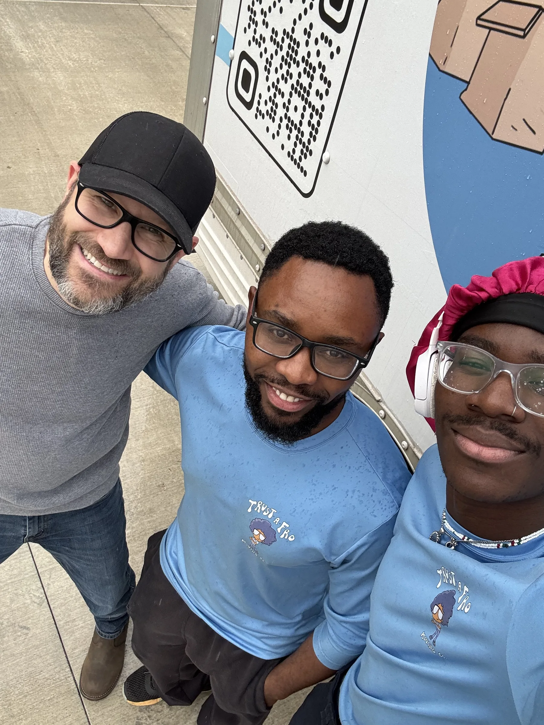 A happy customer taking a selfie with two Trust A Fro movers