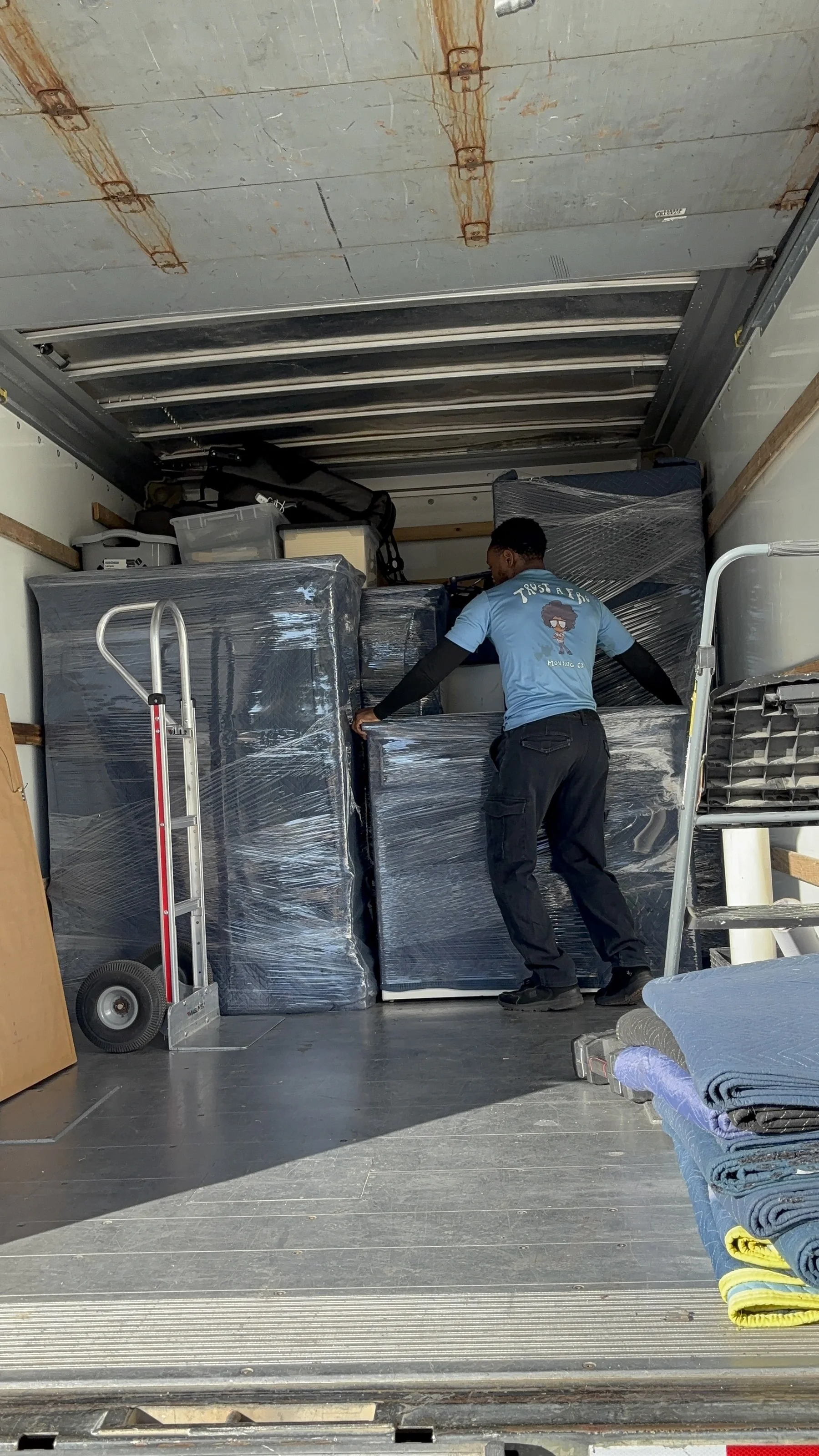 A truck neatly loaded with furniture wrapped in plastic